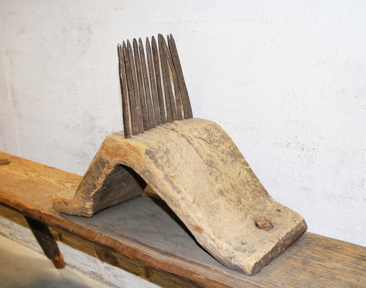 Hörepa på bänk. Sadelformad, böjd träskiva med järntinnar, fäst på långt bräde, som står på fyra svängda ben. (Gunnar Blomgren, år 1909)