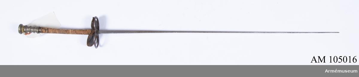 Florett, G. Pion, Frankrike ca 1910.
Hög, profilerad knapp av bly(?) i form av 5 räfflade ringar med skålade partier däremellan, den översta ringen störst och sedan nedåt avsmalnande, den nedersta återigen något större än den närmast ovanför. Parerplåt i form av två ovala ringar av stål, ovanför ringarna en skinnplatta av samma form, narvsidan uppåt, undersidan svart.

Svagt böjd, fyrsidig kavel lindad med tre parter tunt lingarn omväxlande med en part grövre, tvinnat garn, upptill och nedtill mässingsringar, den övre rund, den nedre fyrsidig, båda med tvåkulbårder.

Fyrsidig, framåt avsmalnande klinga med avbruten spets. 75 mm från fästet signering: "G. PION", närmare fästet en stämpel i form av ett gående lejon samt vid fästet 5.