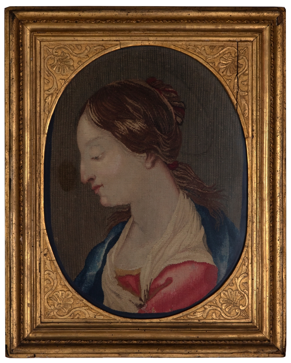 Brystbilde av kvinne/madonna sett i profil fra venstre. Kvinnen har nedslåtte øyne og brunt hår med røde bånd. Hun er iført en rød kjole, blå kappe og et lyst tørkle. Bildets bakgrunn er grå.