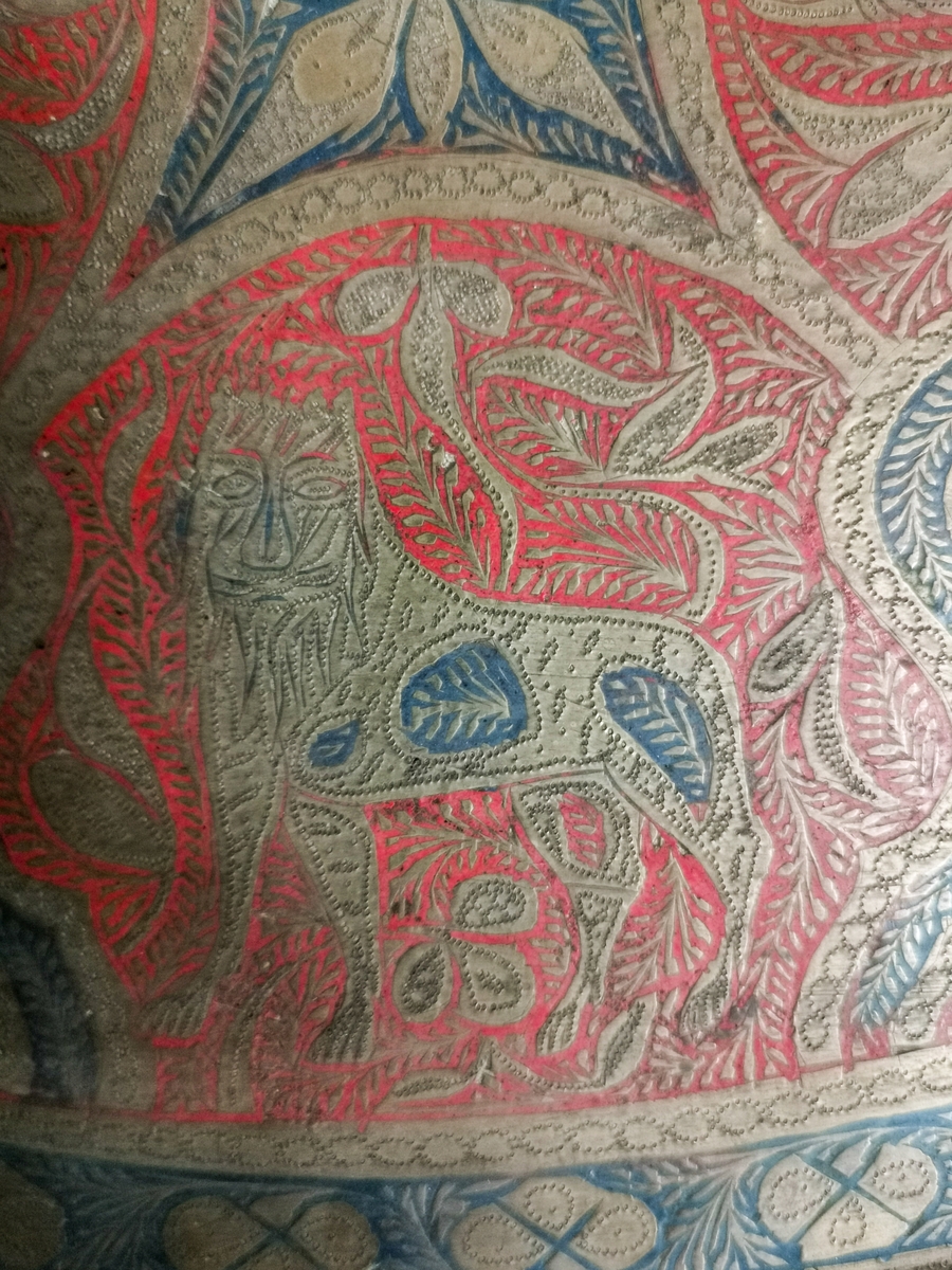 Motiv med jaktscene. Siselert dekor, malt i rødt og blått. Asiatisk. Fremstiller jeger på hest, en tiger med menneskelignende trekk, et hjortedyr, elefant med rytter ikledt kjortel, turban. Med gevær.