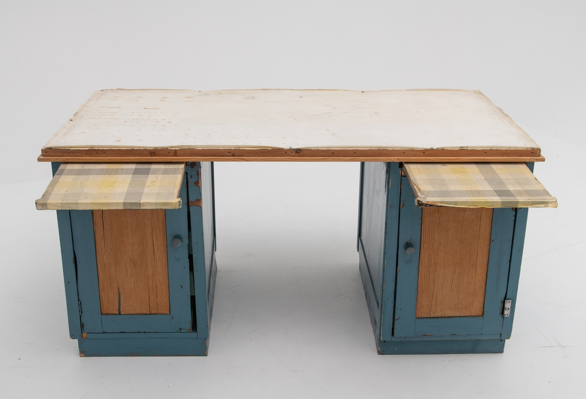 Bord, arbeidsbord for fluebinding,  som består av tre deler: to skuffseksjoner og en bordplate som ligger løst oppå skuffeseksjonene. 

Opprinnelig registreringstekst fra mottaksprotokoll: 
"Arbeidsbord for fluebinding, fra Engerdal, Hedmark. Tre, voksduk. Bordplate 74,5 x 149 cm. H. 74 cm. Arbeidsbordet er laget av et gammelt skrivebord. Det består av to skuffseksjoner, 44, 5cm brede, med plate på toppen. Skuffeseksjonen er malt blå, bortsett fra speilene i dørene som er trefarget. Uttrekkbare plater over skuffene er dekket med rutet voksduk. Bordplata har hvit voksduk. 
Arbeidsbordet er tatt i bruk av John Sand, giverens far,  i 1920-30 åra. Brukt av ham til 1966-67. Deretter brukt av Erling Sand til januar 1973.
Giveren er Erling Sand, Heggriset, Engerdal."