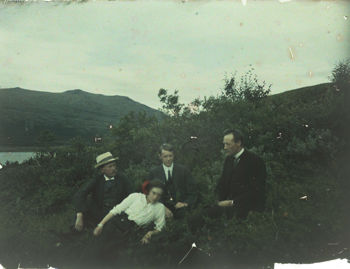 Fargebilde av tre menn og en kvinne som sitter like ved Sjodalsvatnet, Iver Storvik til høyre i bildet