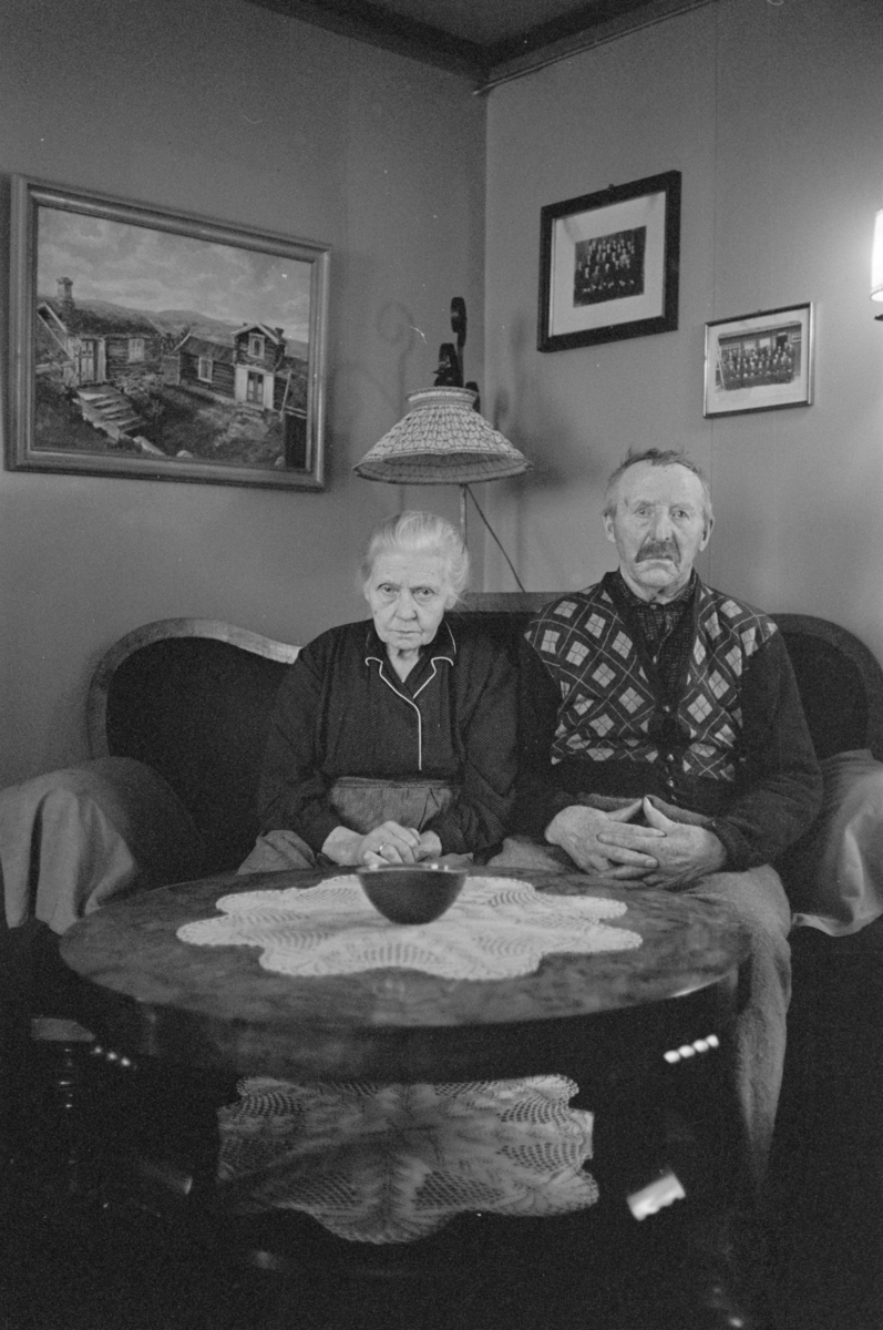 En kvinne og en mann sitter i en sofa.