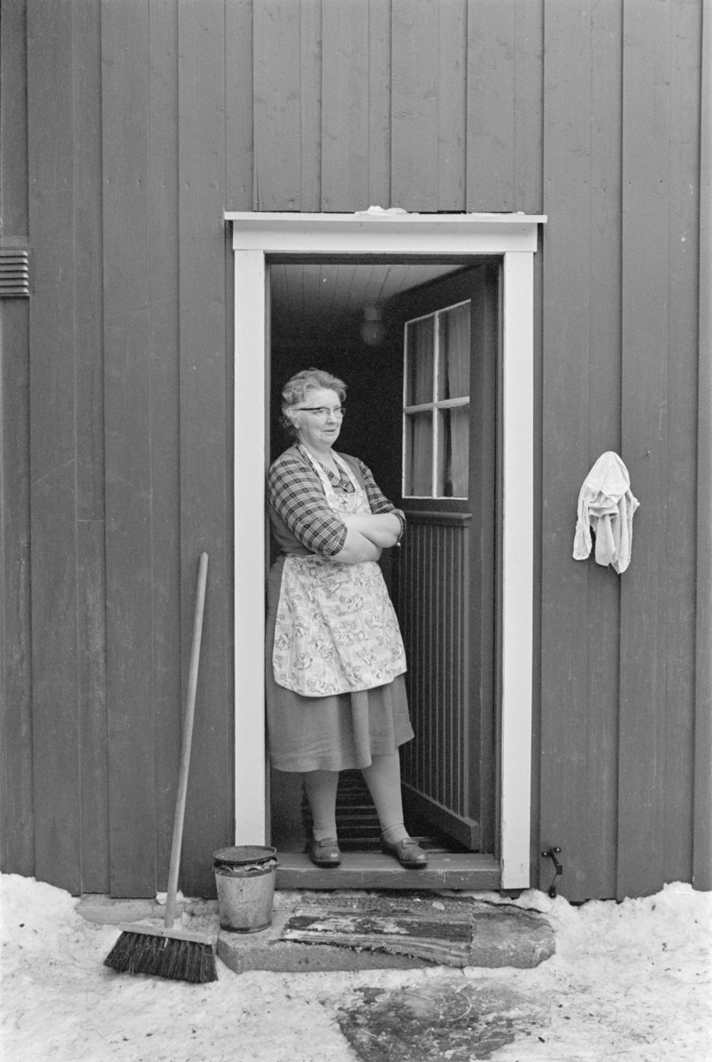 En kvinne står i en døråpning.