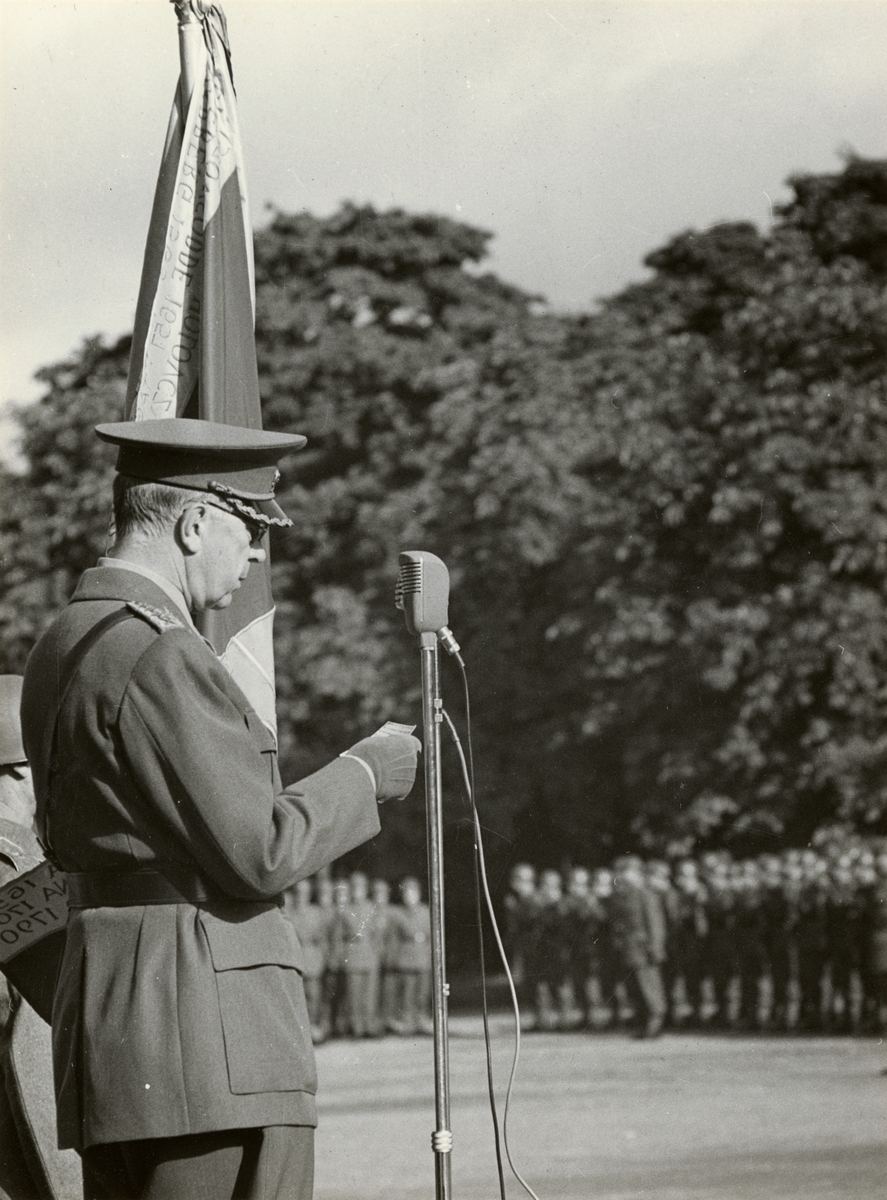 Text i fotoalbum: "H.M. Konungen talar till Kungl. Upplands regemente i samband med överlämning av ny fana 27 september 1955."