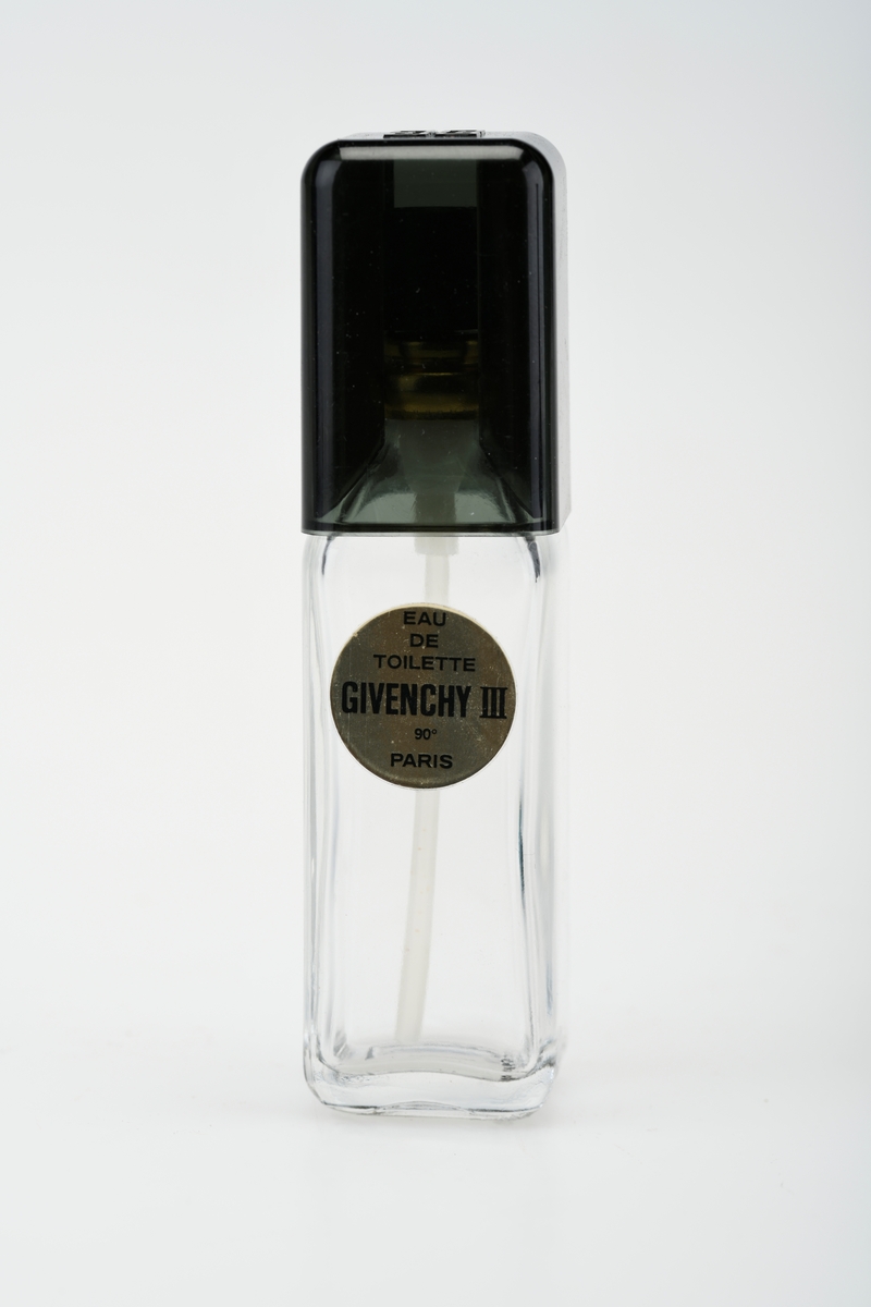 Parfymeflaske av typen Givenchy III som ble lansert i 1970. Flasken ligger i original eske. Esken er firkantet og lokket åpnes i front slik at parfymen står på utstilling. Lokket lukkes med en klaff på siden. Esken er av brun papp med sølvmønster og tekst i sølvfarge. På baksiden er det prislapp fra Domus. Flasken er av klart glass og er firkantet (kvadratisk i bunnen). På forsiden er det et gullklistremerke med svart tekst. Korken er firkantet og mørk grågrønn på farge. For tekst på eske og flaske, se "Påført tekst/merker".