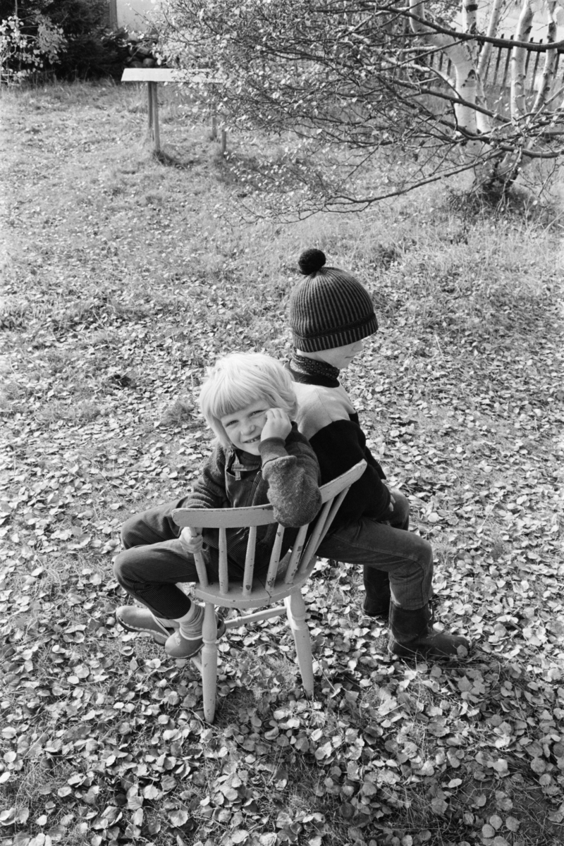 Portrett av to barn sittende på en pinnestol.