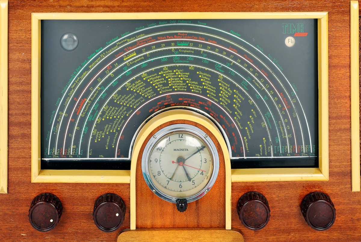 Radio i tre med gule lister, høytaler på hver side og display med klokke i midten.