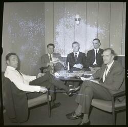 Fotografi av mange menn kledd i dresser med slips som sitter