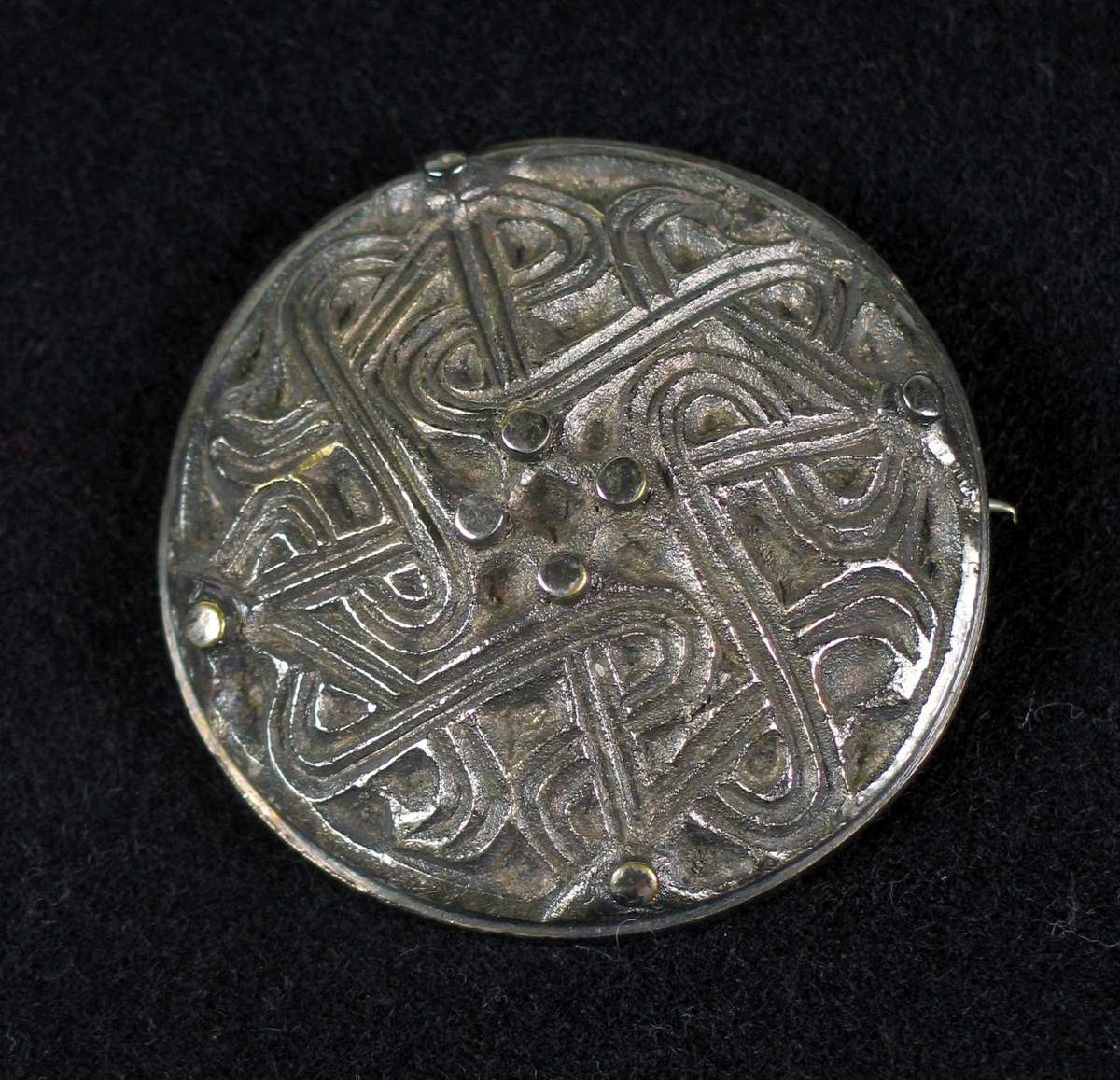 Rund støpt nål i sølv (tinn?) med nordisk mønter.