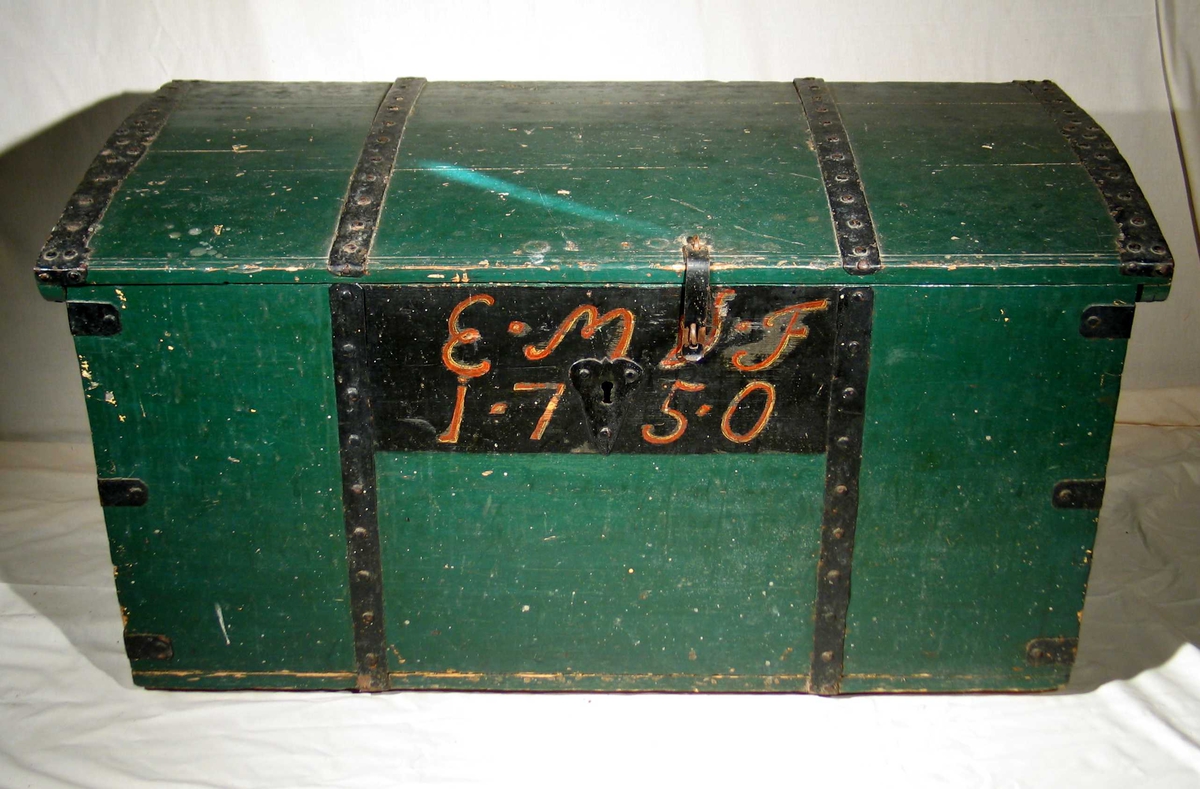Grønnmalt trekiste med tappede hjørner. Stort svart felt i front med påmalte initialer og årstall. Kisten har c-formede håndtak på siden, beslag og hengsler i jern.