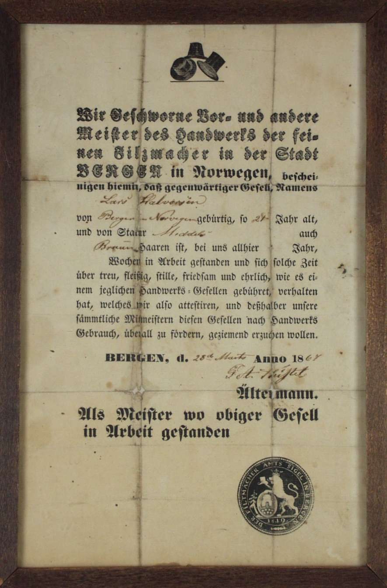 Mesterbrev med emblemet til filtmakerlauget i Bergen fra 1819. Det er rammet inn med enkel treramme.
Teksten står på tysk.