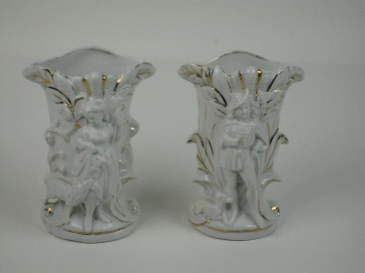 Porselensvaser med dekor i form av bladverk med gullkonturer. Den ene har en framstilling av en gjetergutt med hund og den andre en gjeterjente med et lam.
