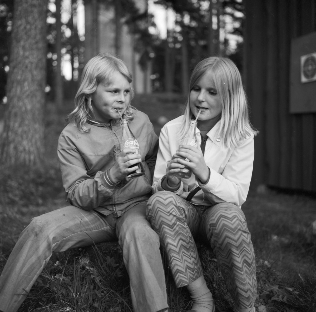 Två flickor sitter ute och dricker Coca-Cola ur flaska, Tierp, Uppland 1969
