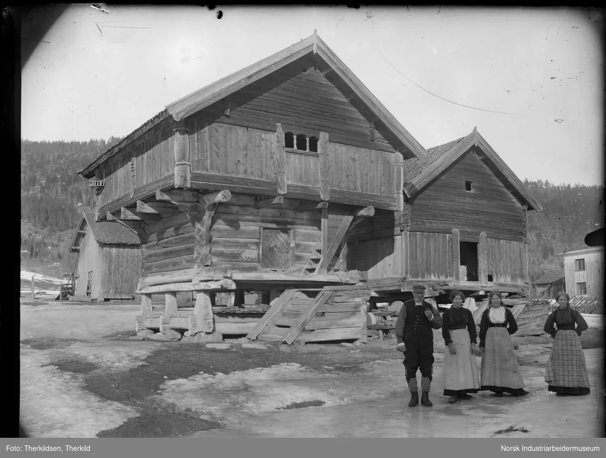 Tre kvinner og en mann stående foran vengebur og loft på Nord-Sem. Fjøsbygning og bolighus i bakgrunnen.