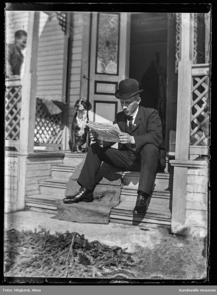 Gottfrid Höglund sitter på trappen till hemmet i Fanbyn och läser tidningen. En hund sitter intill.