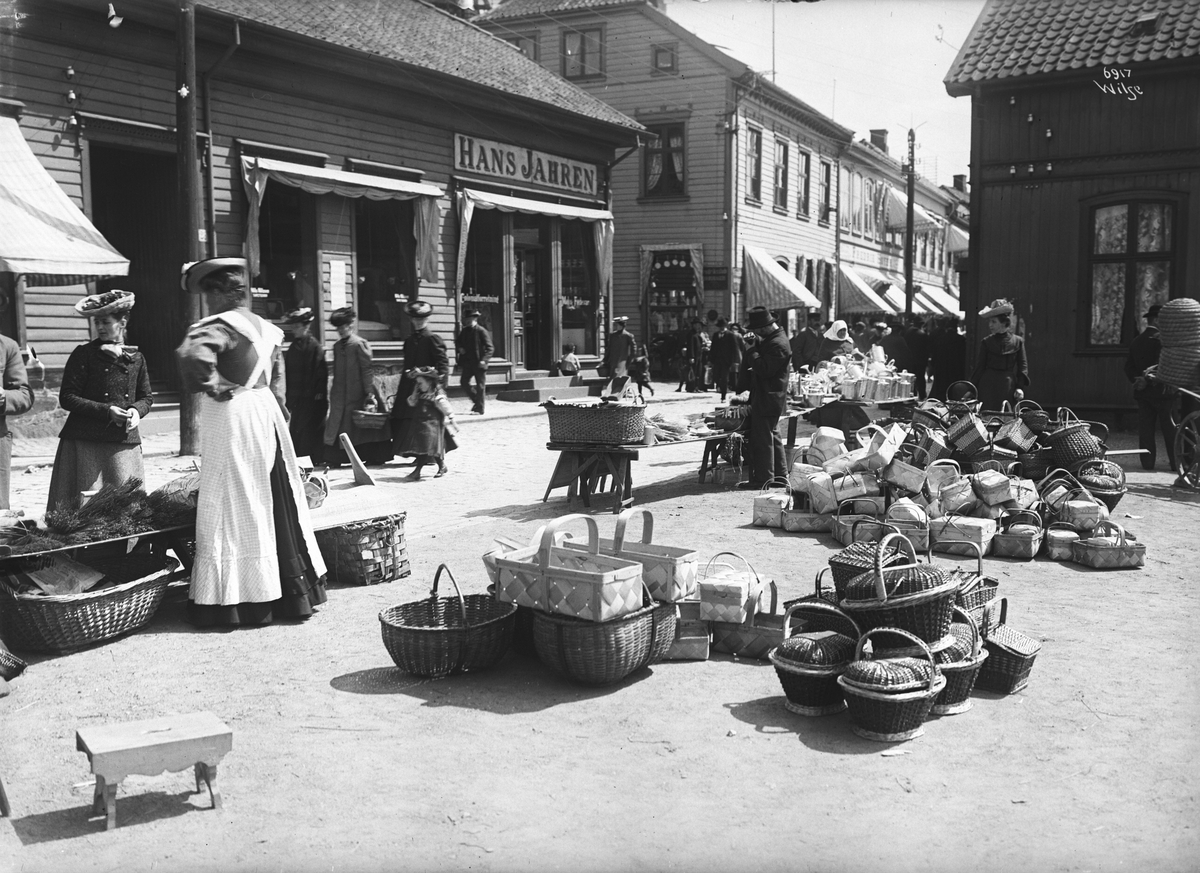 Husflidstorget i Fredriksstad. Salg av flettede kurver, metallkanner og spann. Fotografert i 1907.