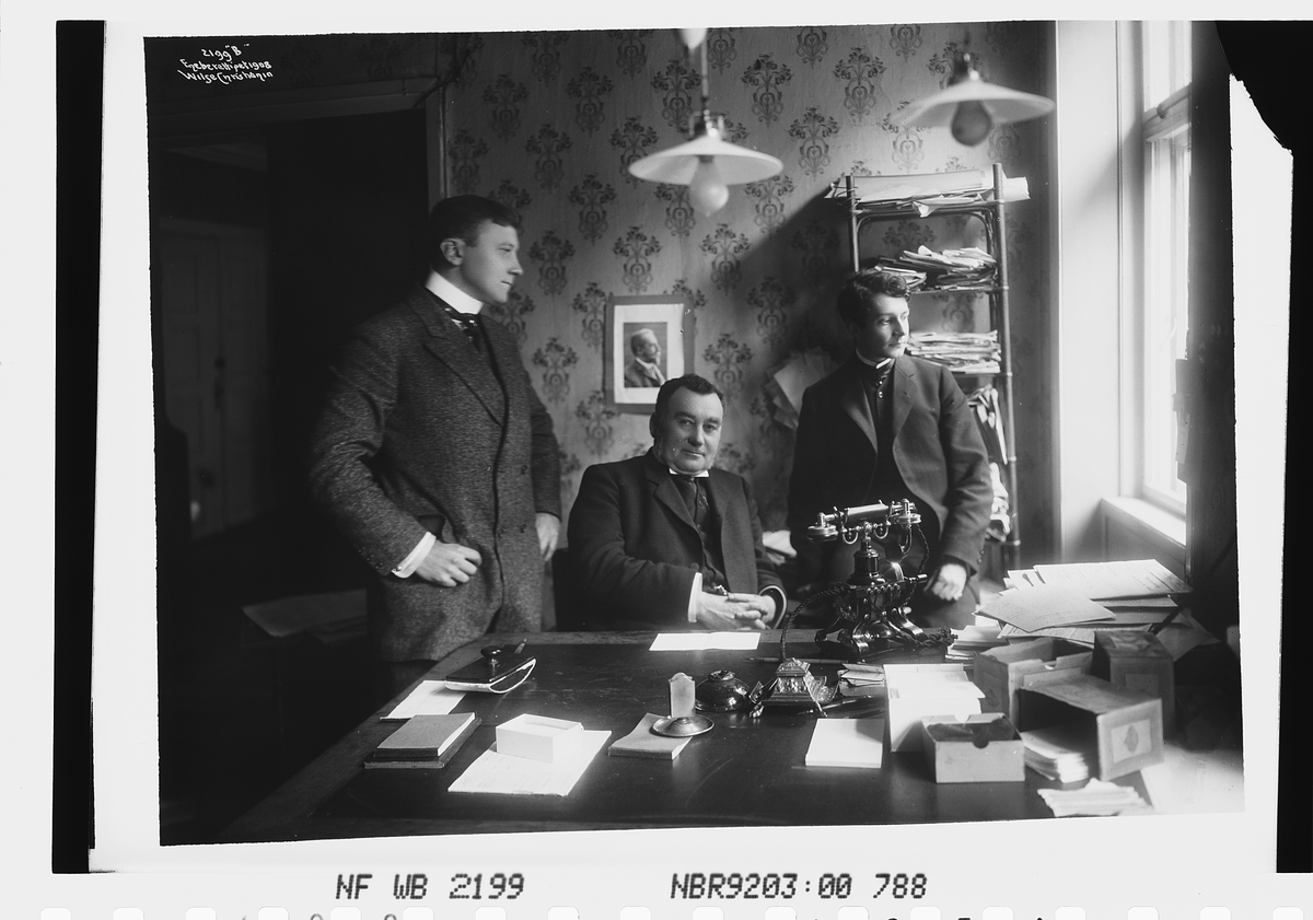 Avisredaktør, antatt Morgenbladet, her fotografert på sitt kontor med sønnen og annen medarbeider.
