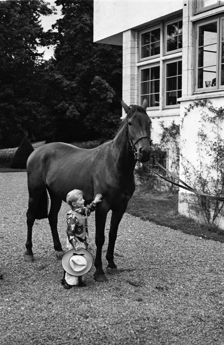 Arveprins Harald i cowboyklær beundrer den flotte hesten utenfor huset på Skaugum.