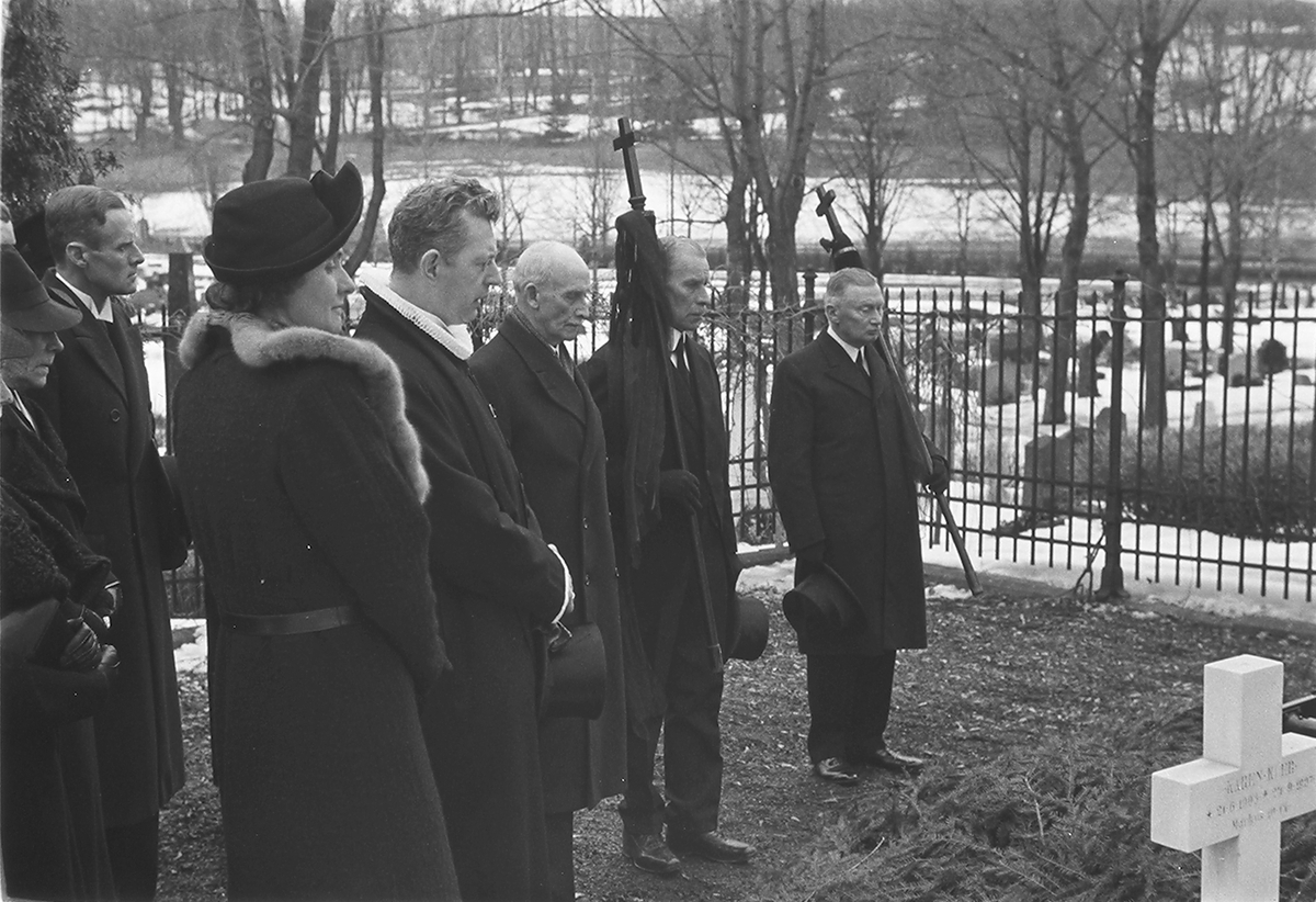 Begravelsesfølget ved båren til fru Kiær. To menn med faner. Fotografert 1940.
