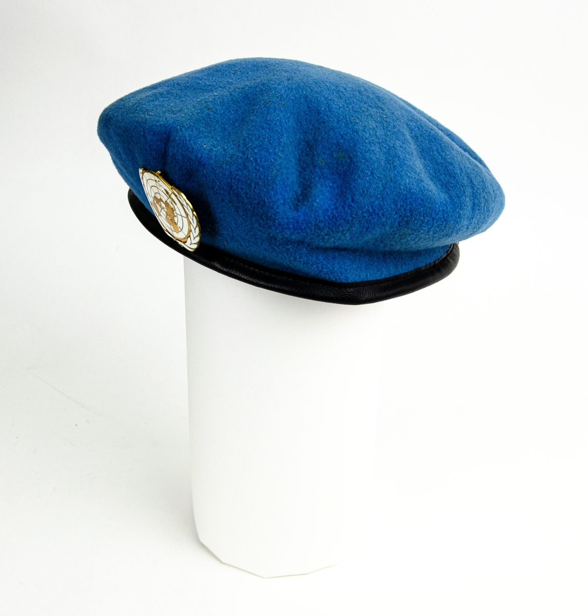 Baskermössan blå, storlek 7 3/8, med FN-emblem. Vit stämpel inuti "7 3/8 KANGOL wear limited".