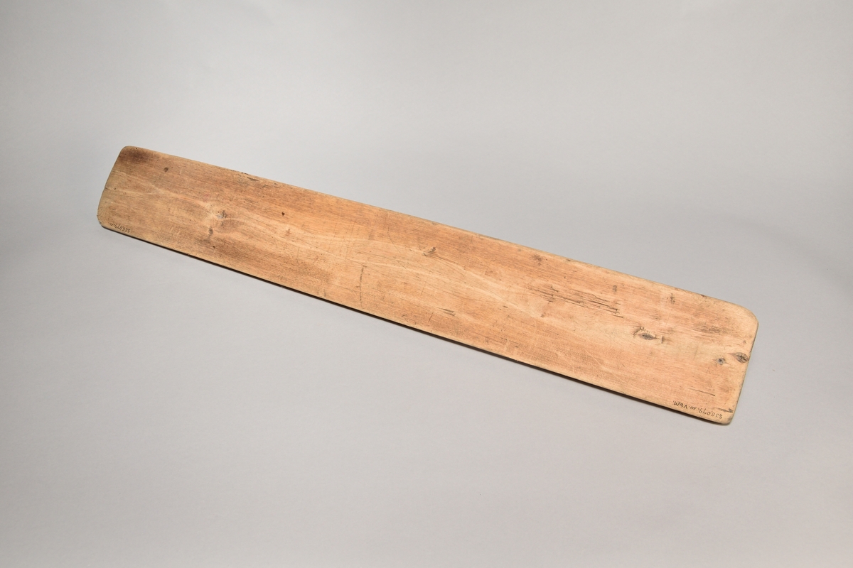 Kaveldon tillverkat i trä, med platt bräde samt skuret handtag. Brädets ovansida ornerat med karvsnitt samt med inskriften: "ANNO: 1723: SAD". 