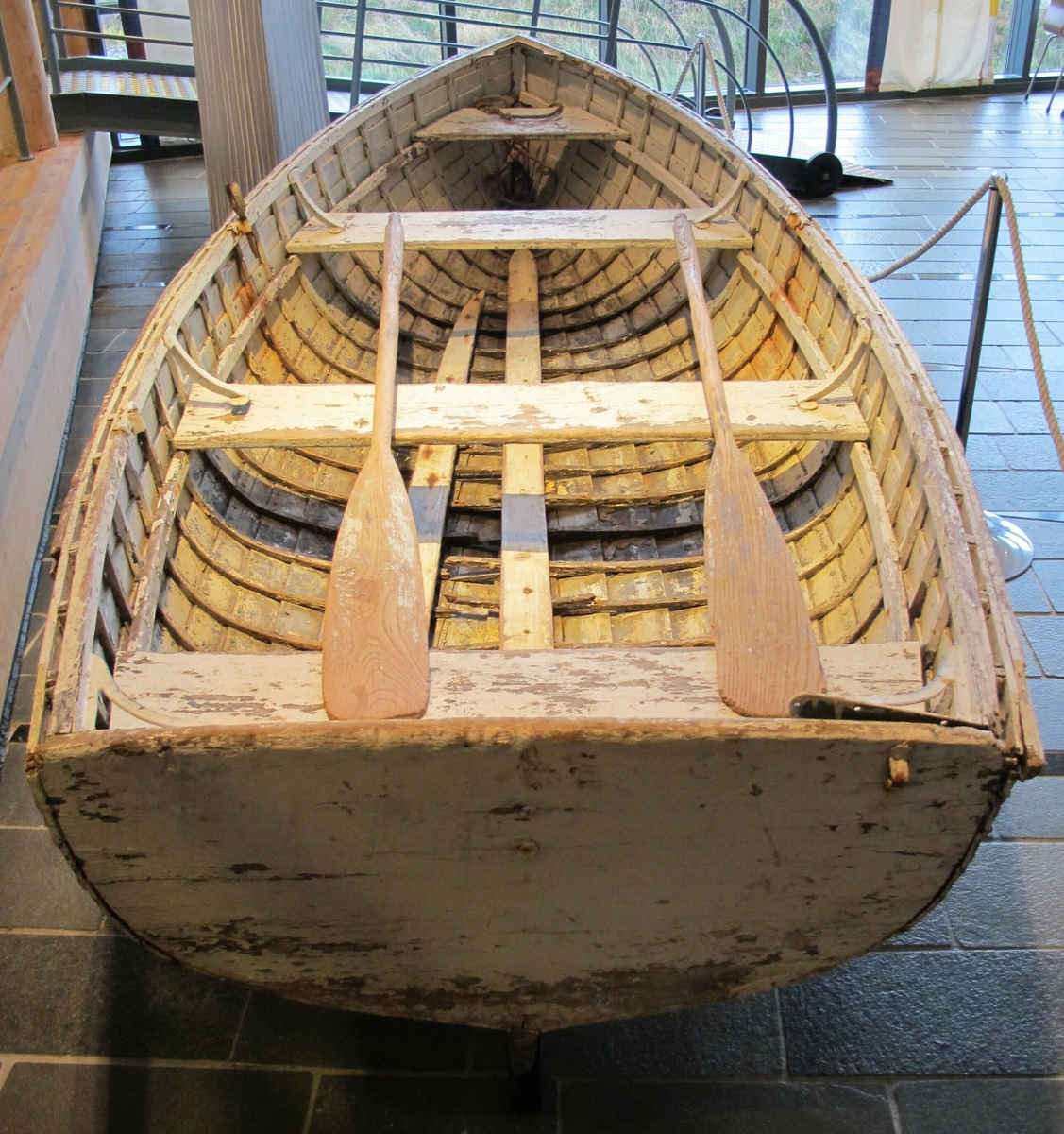 Hvitmalt livbåt med omtrent ni bordganger, tre tofter og tre åregaffelholdere (en mangler).