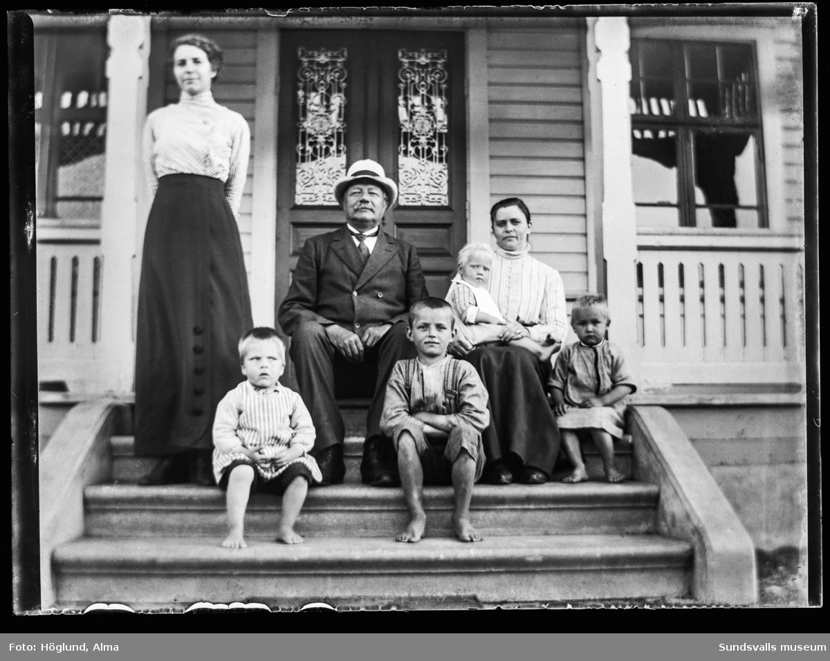 Gruppbild med två kvinnor, en man och fyra barn på brokvisten till ett hus, troligen är det Logården i Västerlo, Stöde Försörjningshem. På bild nummer två är bara de vuxna med.