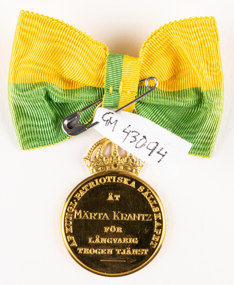 Medalj i etui från Kungliga patriotiska sällskapet till Märta Krantz, för Lång och trogen tjänst på Nordiska museet. Guldmedalj med grönt och gult band.