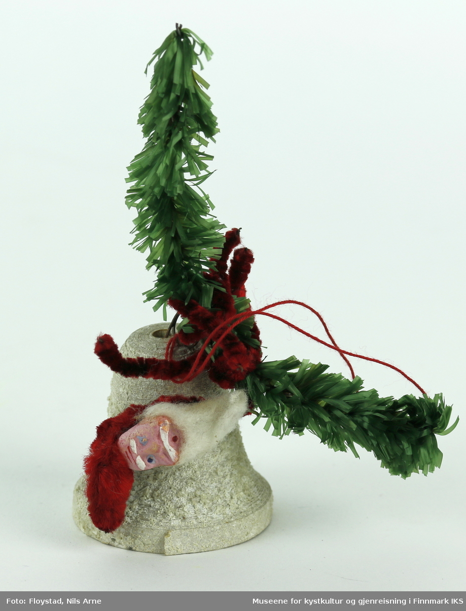 To juleklokker/ bjeller en liten og en stor med dekor av nisser og kunstige grangrener. Hver bjelle har dekor av kunstige grangrener og mørkerøde piperensere med et pålimt ansikt av en nisse. Nissene har hvite øyenbryn og blå øyne, med hvit bart og bomullsskjegg. Selve juleklokkene/ bjellene er laget av pappmasjé og er malt hvite, og dekorert med grovkornet glitter som gir bjellene en ruglete overflate.