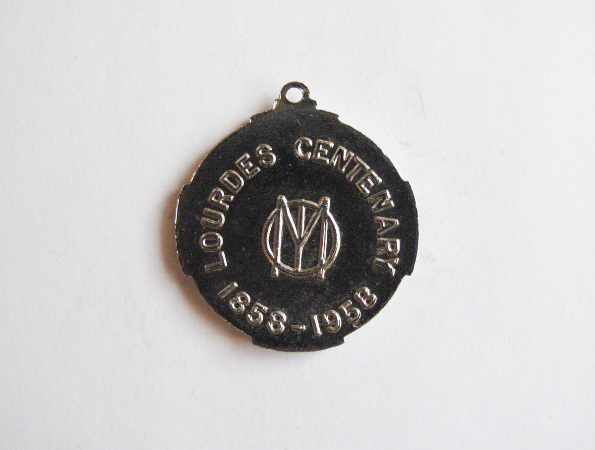 Motiv advers: I rund medaljong i korsskjæringen på et malteserkors står et pasjonskors i stråleglans.

Motiv revers: Tekst om Maria-monogram.