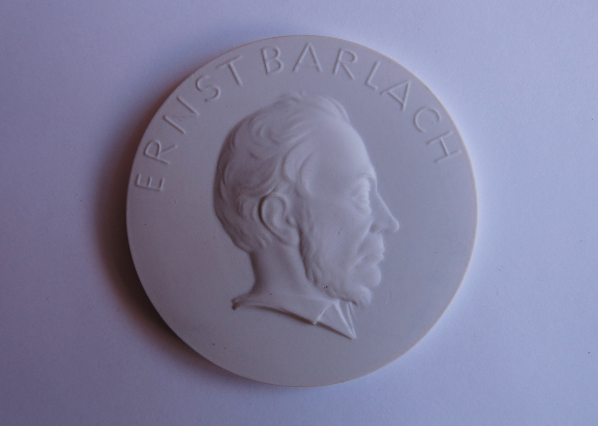 Motiv advers: Billedhuggeren Ernst Barlach i profil mot høyre.

Motiv revers: Årstall. Nederst symbol.
