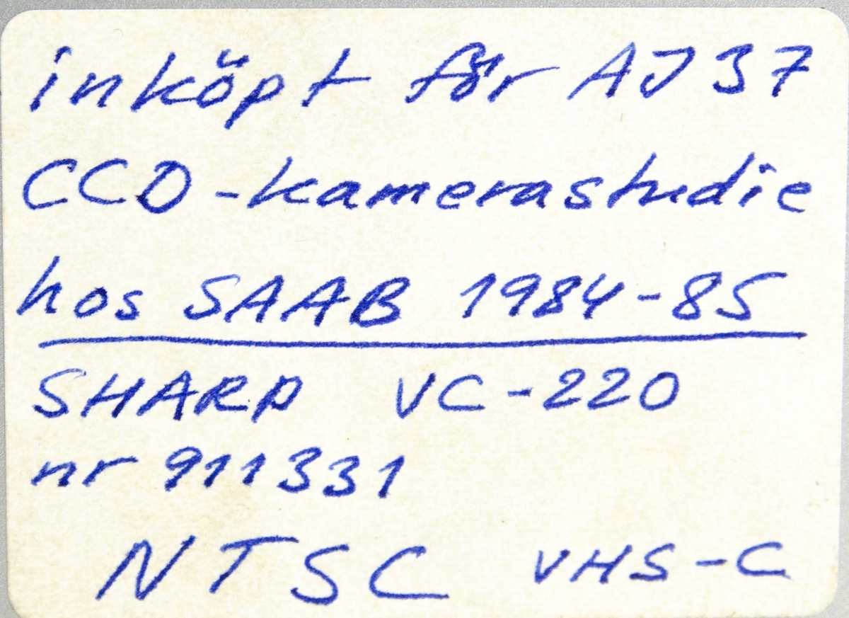 Videobandspelare VC-220, tillverkad av Sharp Electronics Corporation i Tochigi, Japan, november 1982. Rektangulärt föremål i grå plast med uttag för att koppla in kamera, mikrofon för inspelning samt skärm och högtalare för uppspelning. Maskinen är utrustad med batteri för att fungera utan kabel och använder kompakt VHS-kassettformat, VHSC. På föremålets sida finns en handskriven anteckning "Inköpt för AJ 37 CCD-kamerastudie hos SAAB 1984-85 Sharp VC-220 nr 911331 NTSC VHS-C".