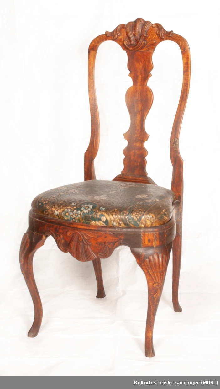 Stolen er av den almindelige rokokkotypen. Ryggen er åpen med et profilert brett som ender i en musling. Sargen har også et usymmetrisk rokokko-ornament. Stolen er trukket med gyldenlær, blå bunn.