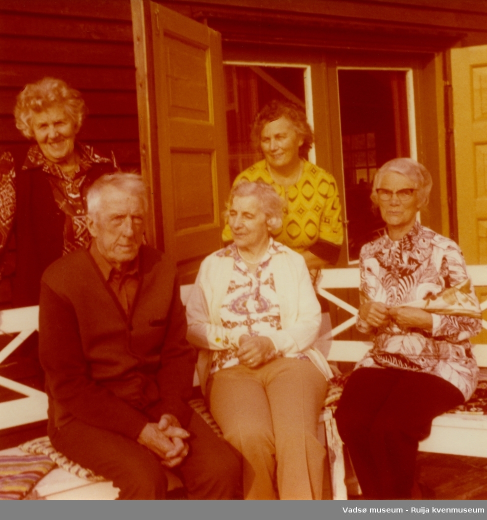 Gruppe mennesker fotografert på trappen utenfor Esbensens hytte i Jakobselv, Vadsø kommune.  Fra venstre foran:  Ingrid Skogsholm, Bjarne Skogsholm. Fra venstre bak: Ella Esbensen og Lilly Simonsen. ca 1970 tallet.