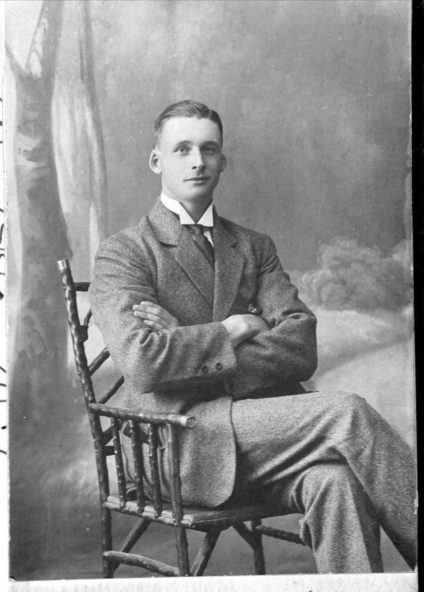 Studioportrett av ung mann sittende på en stol.