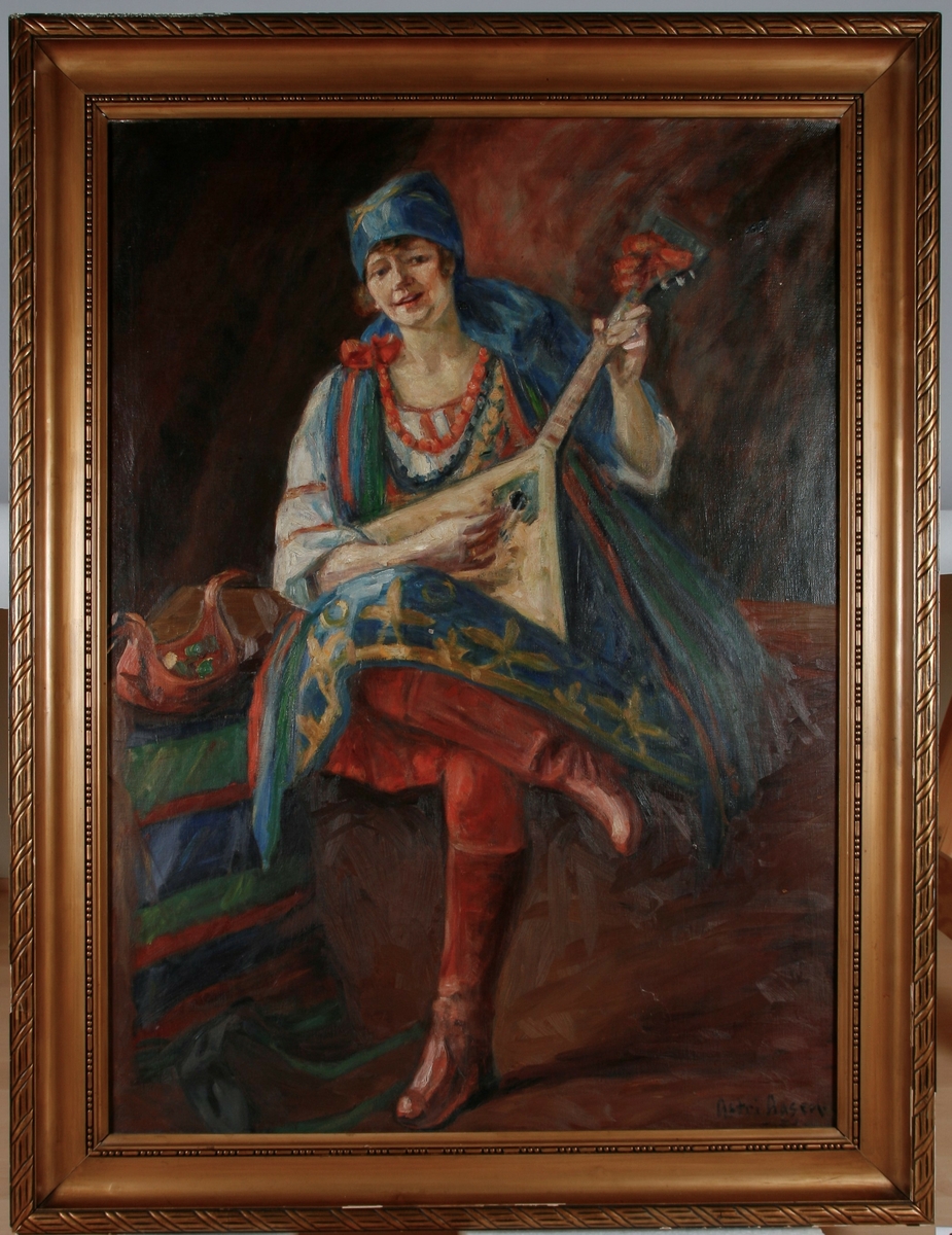 Victoria Bachke ikledd russisk folkedrakt. Hun spiller på et instrument, en balalaika(regnes som Russlands nasjonalinstrument). Ved hennes side en rød ølhøne.