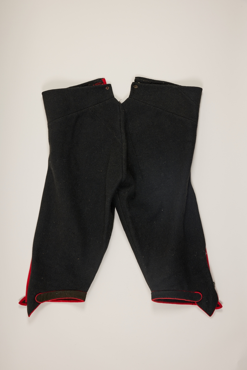 Svarte bukser med rød kanting av ull.
