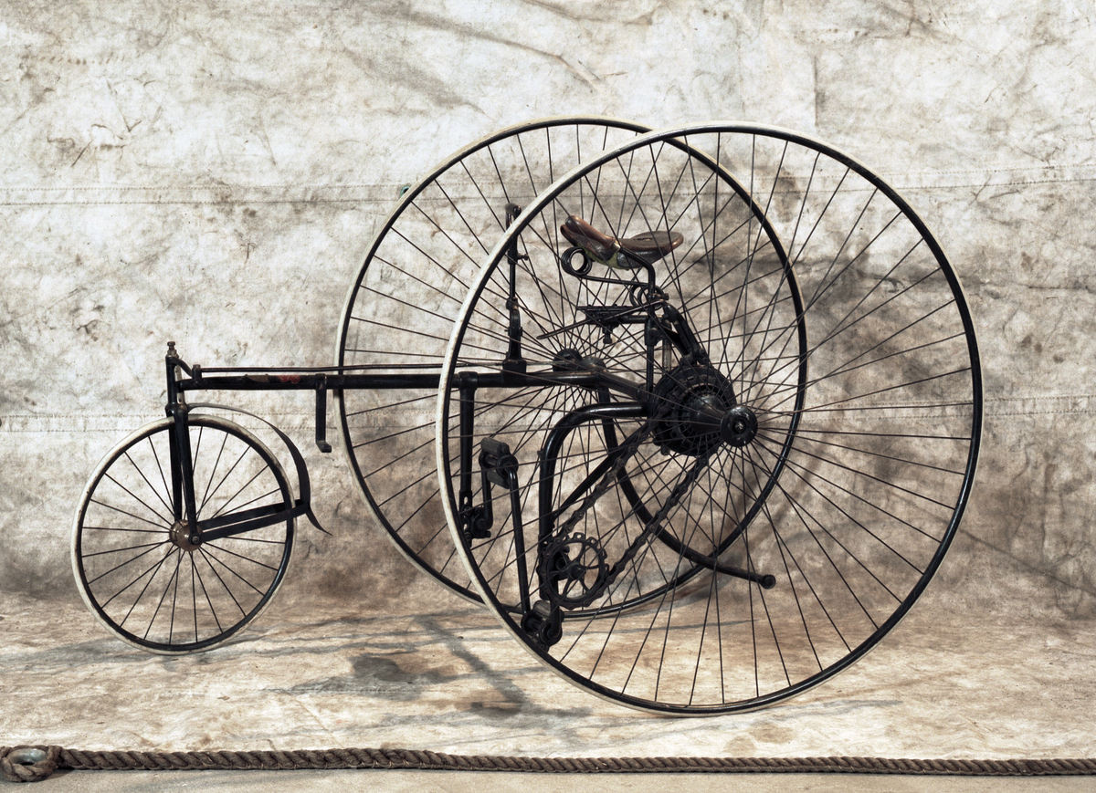 Trehjulig cykel. Styrning med högerhandshandtag som påverkar kugghjul-kuggstång. Bromshandtag för vänsterhand. Kedjedrift. Två stora bakhjul, ett litet framhjul och "damsadel", vilken är mycket trasig. Massiva däck. Märkning: The Royal Mail Tricycle, på sköld av mässing. Röd dekal: The Royal Machine Manufacturing Co Ltd, Birmingham.