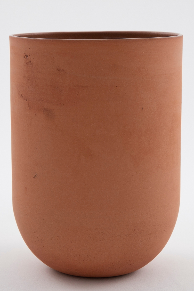 Brun vase i terrakotta. Sylinderformet korpus med bunn formet som en halvsfære. Åpen munning. Uglasert på utsiden og glasert på innsiden.