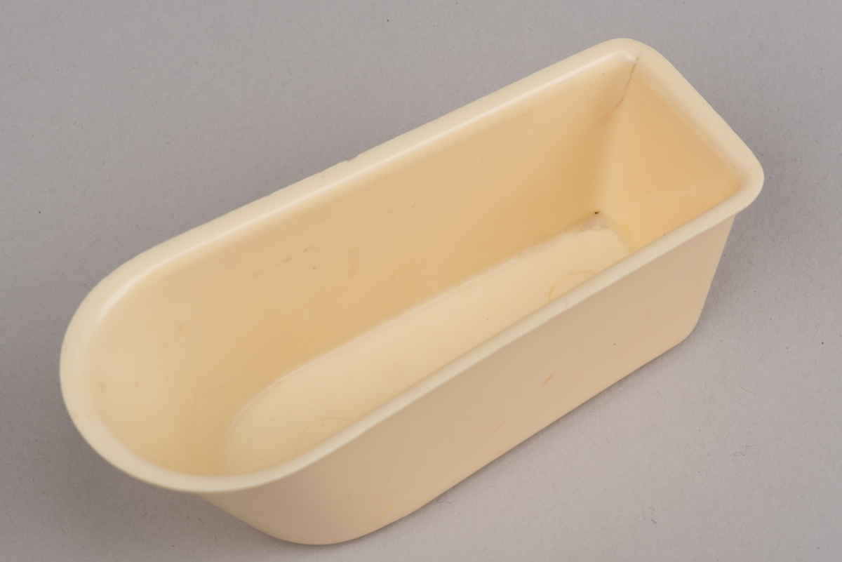 Dockskåpsinredning i form av ett beigt badkar av plast.
Rektangulärt badkar med en rundad och något förhöjd kortsida. Badkaret har fem låga fötter samt en utvikt kant.