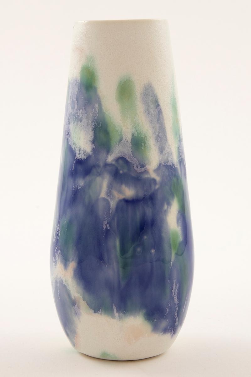 Blank hvit, balusterformet porselensvase med åpen munning. Brede strøk med blå og grønn glasur på korpus. Enkelte krystaller i glasuren.