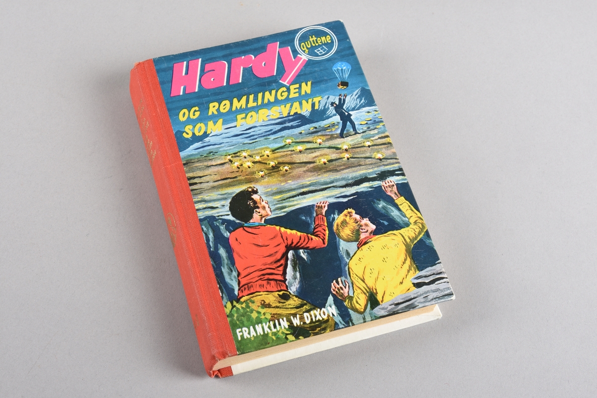 Barnebok nr. 40 i serien om "Hardy-guttene". Boka har shirting i ryggen. Stive permar trekt med papir med fleirfarga motiv på framsida, tekst på baksida. Gullfarga trykk på ryggen. 142 sider.