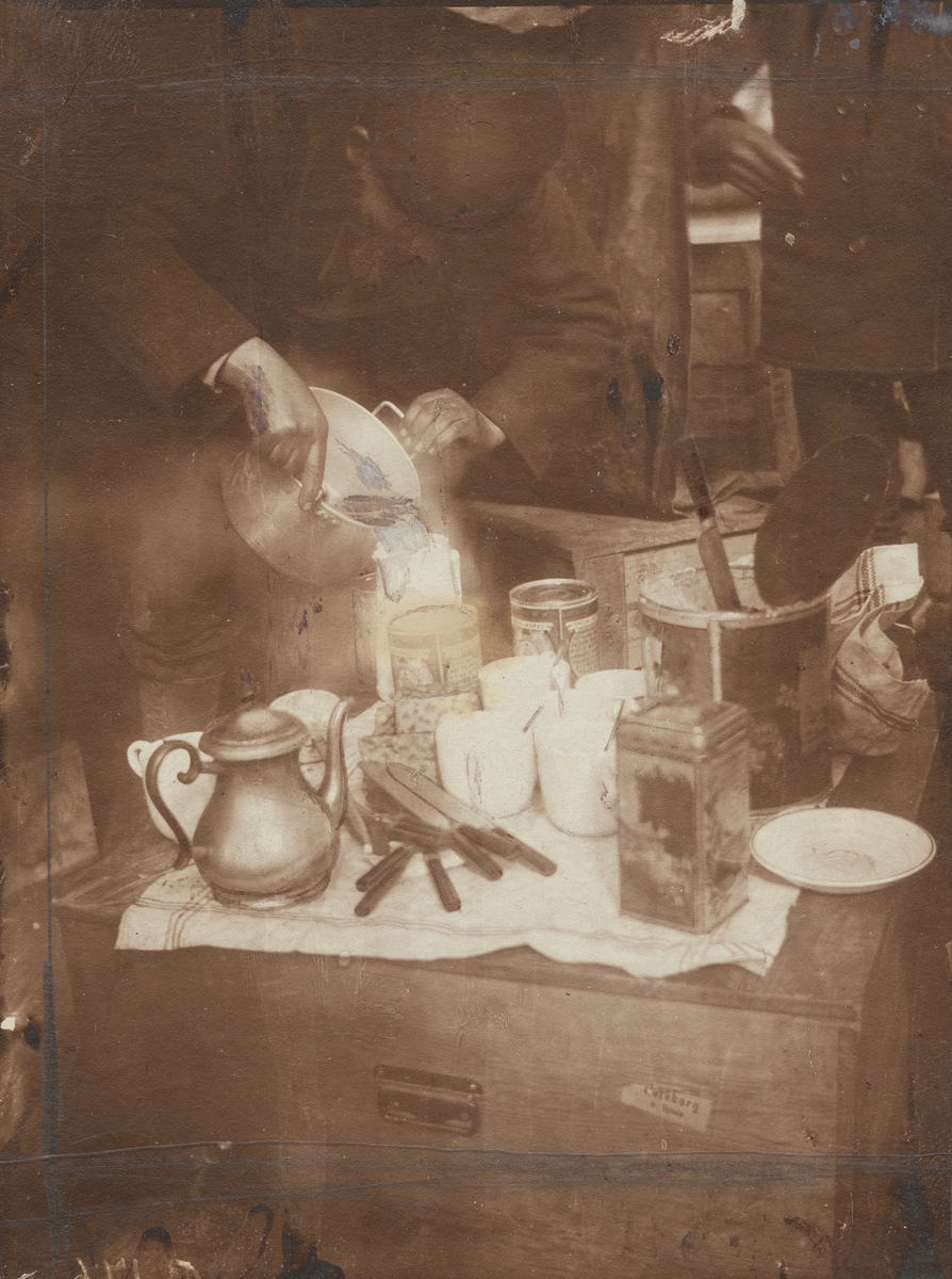 Fotografi från första svenska Antarktisexpeditionen 1901-1904. Motiv av Otto Nordensköld som tillreder kaffe genom att hälla varmt vatten ur en kastrull.