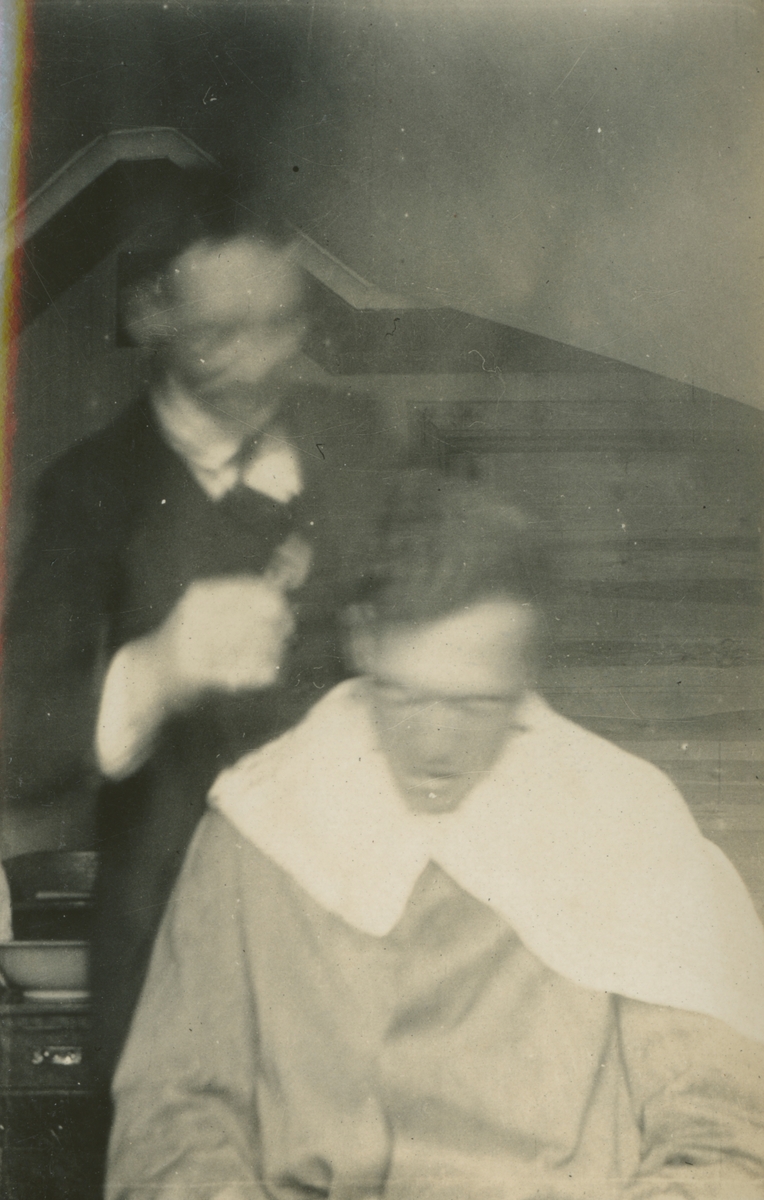 Fotografi från expedition till Spetsbergen. Motiv av en man som får sitt hår klippt av en annan man.