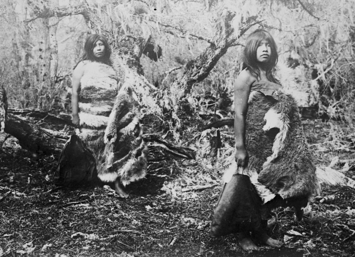 Fotografi från Eldslandet. Motiv av två kvinnor i djungel som är klädda i djurhudar.