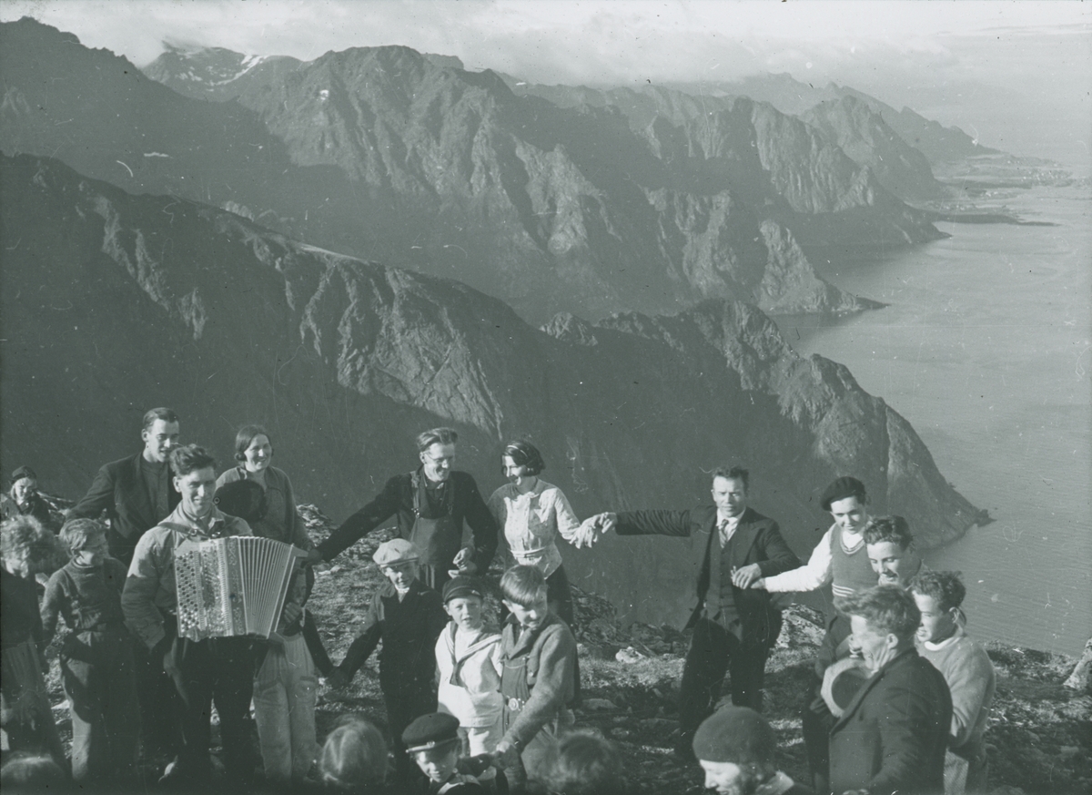 Fotografi från expedition till Spetsbergen. Motiv av en grupp människor som dansar till dragspel på berg.