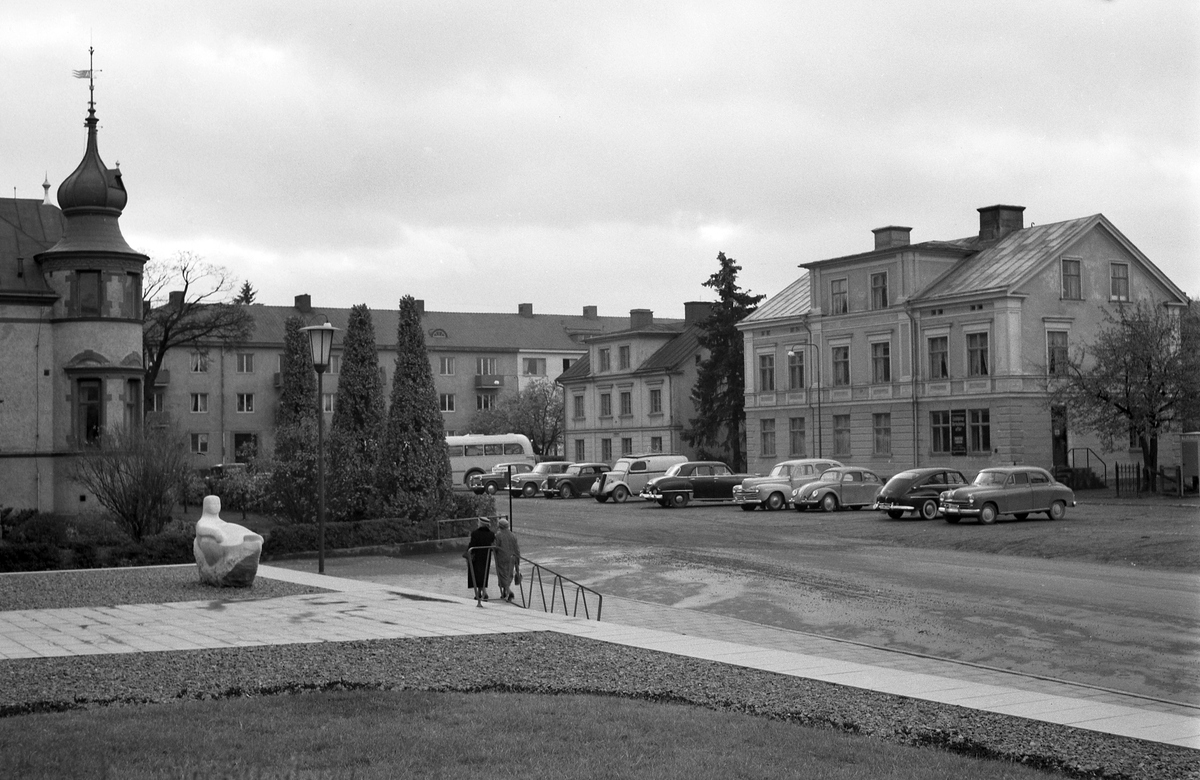 Vy över Magasinstorget i Linköping i en tid då platsen ännu var öppen och obebyggd invid Hamngatan. Torgets namn är kopplat till det kronobränneri som anlades på platsen i slutet av 1770-talet och vars stora brännvinsmagasin låg där fotograf Fromholtz placerade sig vid fototillfället. Nu -läs då- hade magasinstomten istället upplåtits för staden elverk, som för övrigt invigts detta fotoår 1953. Det forna torgets yta är sedan 1980-talet helt uppslukat av en breddad Hamngata.
