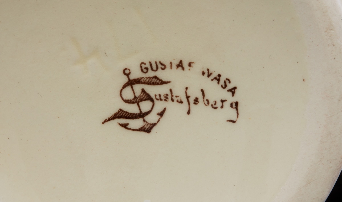 Mugg av porslin med hänkel. Insvängd mynning. Dekor: Gustaf Wasa vid Ornässtugan. Under: 'Gustaf Wasa, Gustafsberg, 174'.