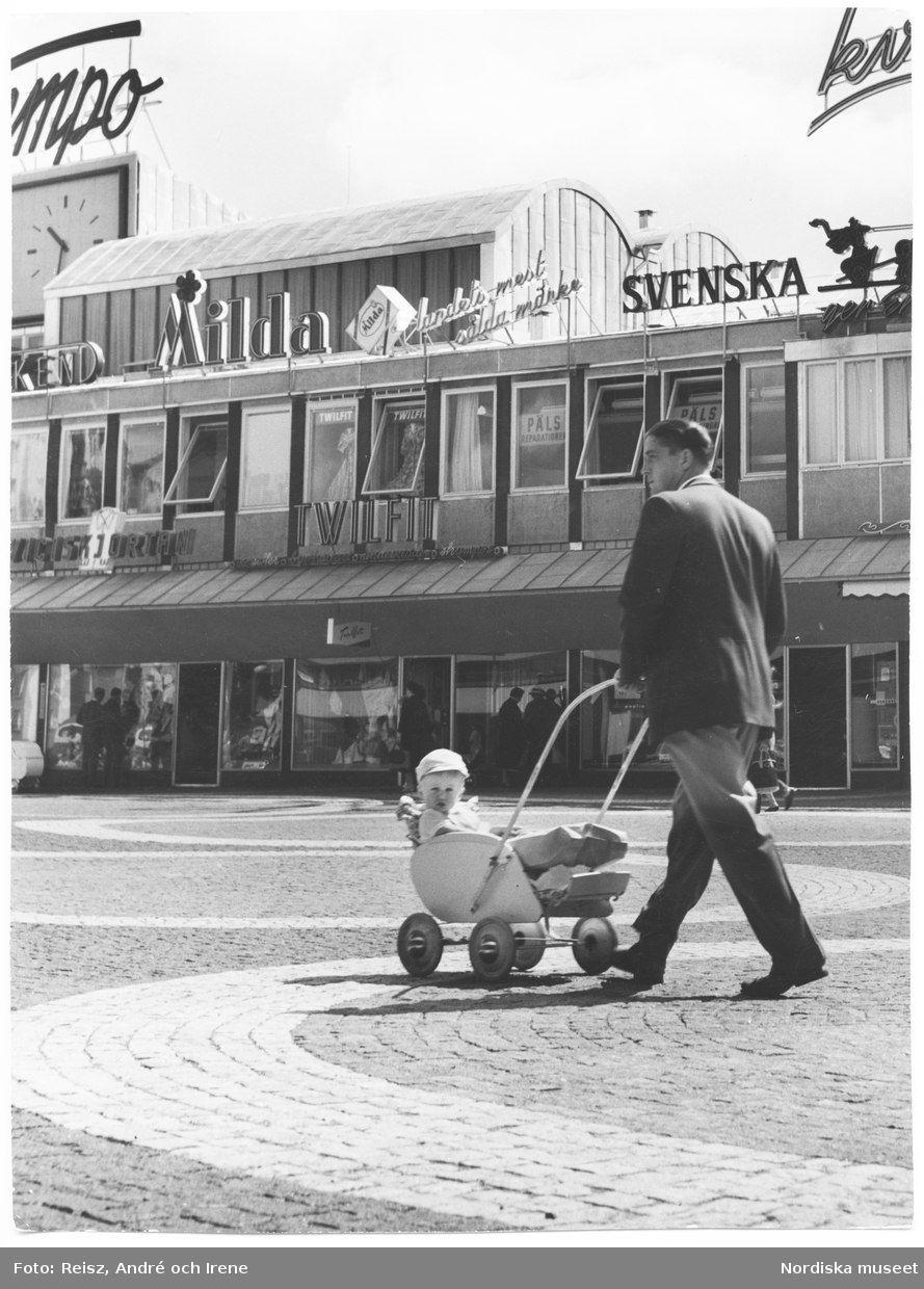 Stockholm. Vällingby centrums affärsgata. Man med barnvagn på torget utanför Twilfit.